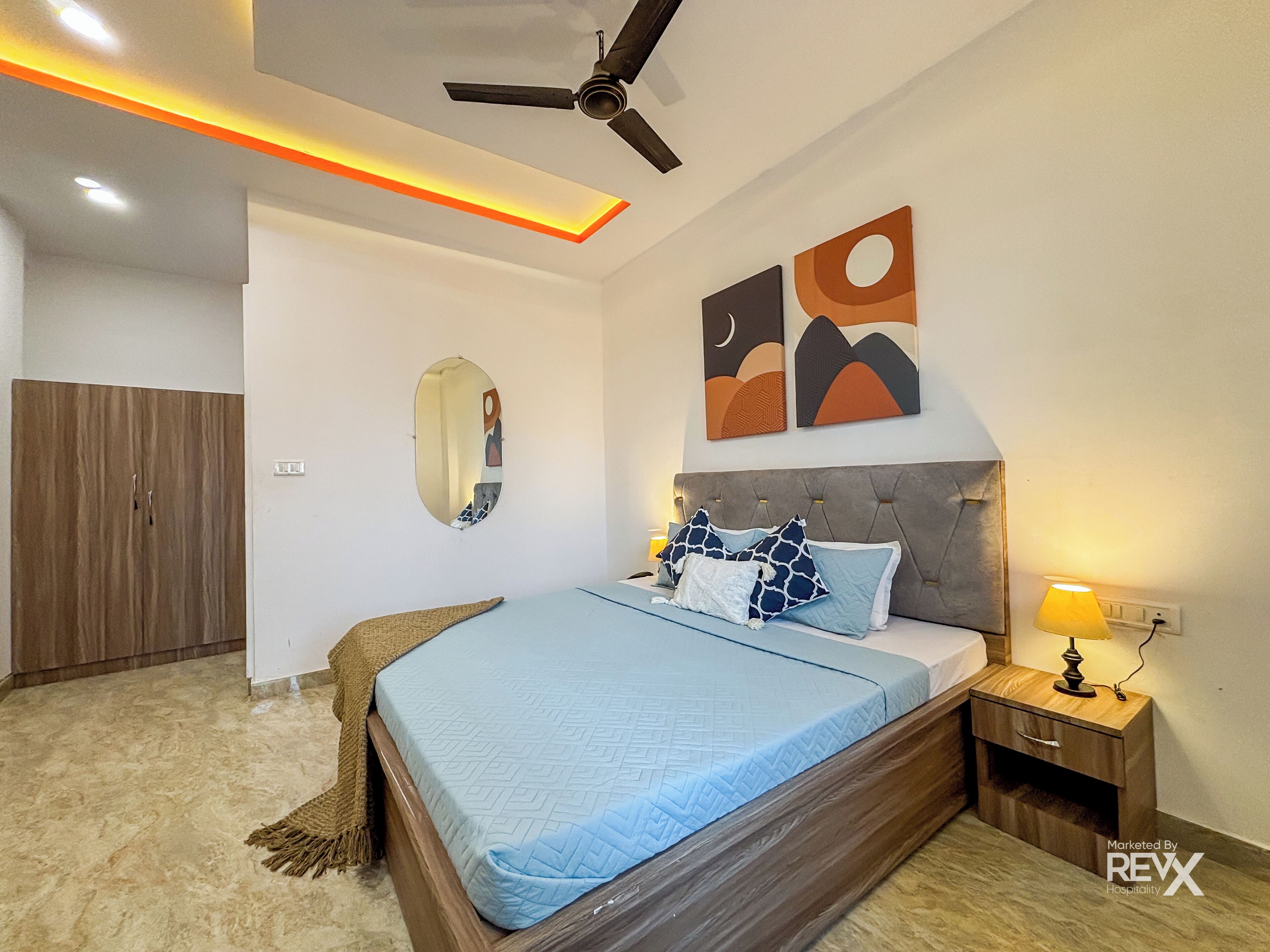 Quarto moderno com cama, mesa de cabeceira e ventoinha no teto.