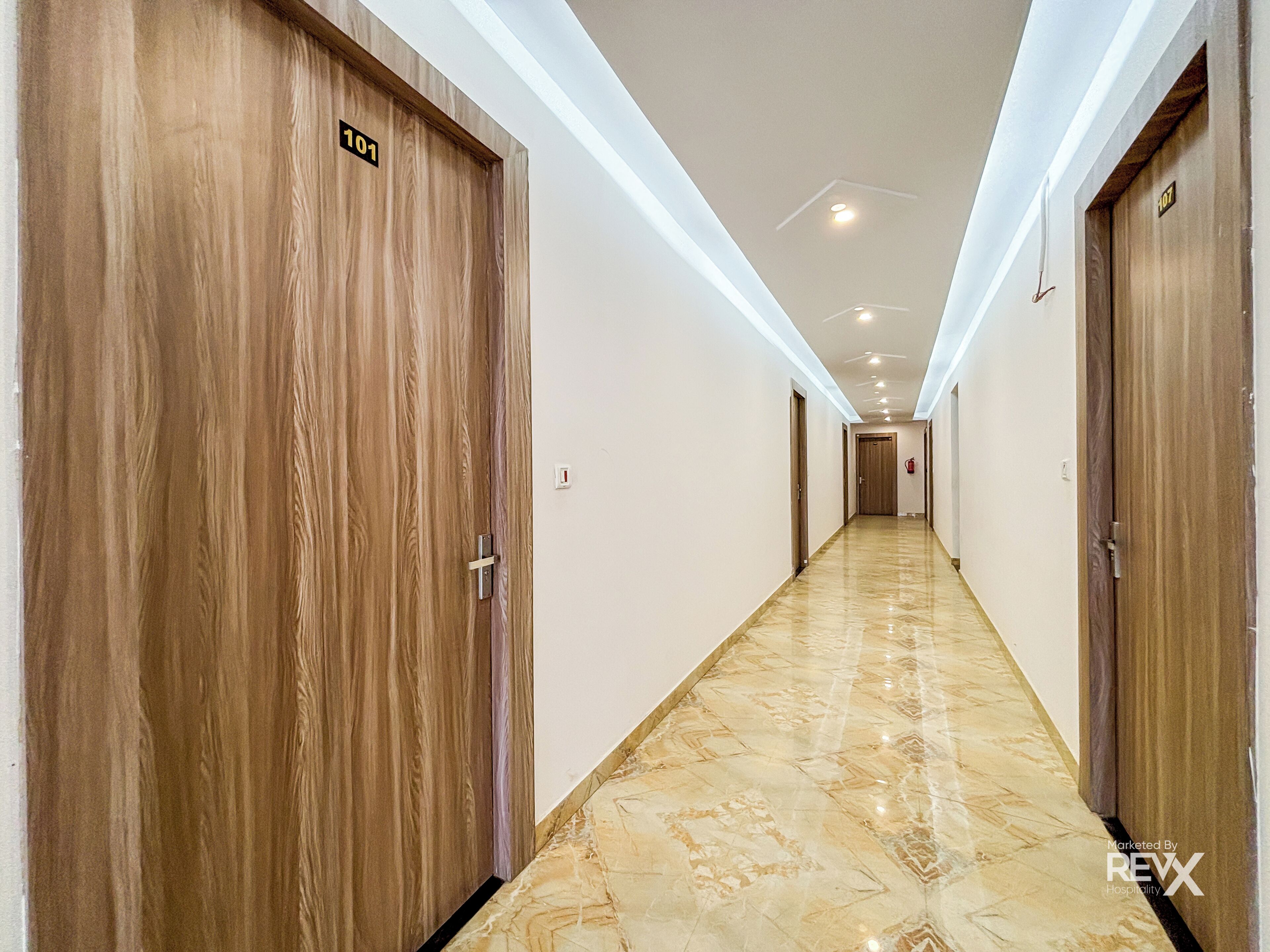 A hotel hallway with wooden doors, numbered 101 and 107, and a marble floor.