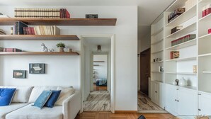 Una sala de estar moderna con sofá, piso de madera y estanterías empotradas con libros y objetos decorativos.