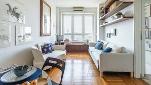 Una sala de estar moderna con un sofá, una mesa de comedor con sillas y un ventanal con vistas a la ciudad.