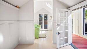 Un pasillo con una puerta blanca que da a una habitación con un sofá verde y una ventana.