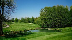 Ein Golfplatz mit Teich, Bäumen und blauem Himmel.