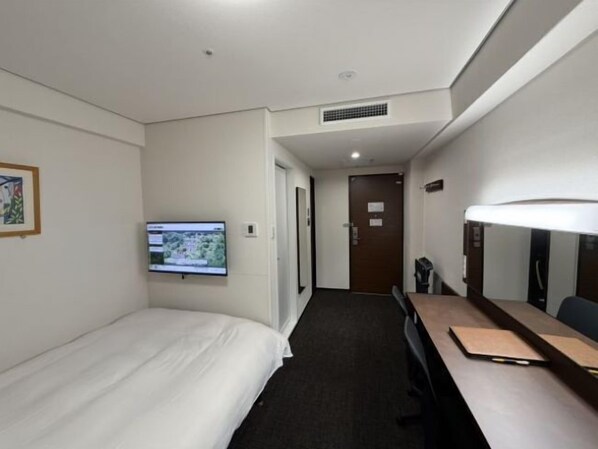 A hotel room with a bed, a desk, a television, and a door leading to another room.