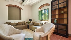 A cozy living room with a sofa, two armchairs, a side table with a lamp, and a large bookshelf. - Tenuta Pian Del Gallo, Greve in Chianti, Florence and Chianti (Greve in Chianti)