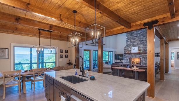 A spacious kitchen with a large island, wooden beams on the ceiling, and a stone fireplace. - Mountain Creek View-Hot Tub - Views - Gas Firepit (Whittier)