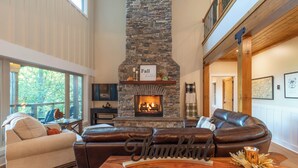A cozy living room with a stone fireplace, leather sofa, and a wooden coffee table with a 'Thankful' sign. - Mountain Creek View-Hot Tub - Views - Gas Firepit (Whittier)