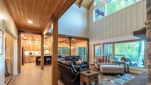 A spacious living area with a leather sectional sofa, a small table, and a stone accent wall. - Mountain Creek View-Hot Tub - Views - Gas Firepit (Whittier)