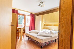 Habitación de hotel con cama, armario de madera y zona de comedor con sillas y una mesa.