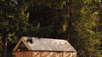 Une cabane en bois avec un toit en pente, une véranda et une personne debout sur la véranda.