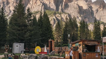 Une cabane en bois rustique, avec une pancarte indiquant « CASSA », située dans une zone montagneuse et dotée de bancs et de tables de pique-nique.
