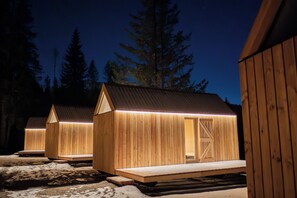 Cabañas de madera con techo metálico, una terraza de madera y una puerta con diseño de travesaño.