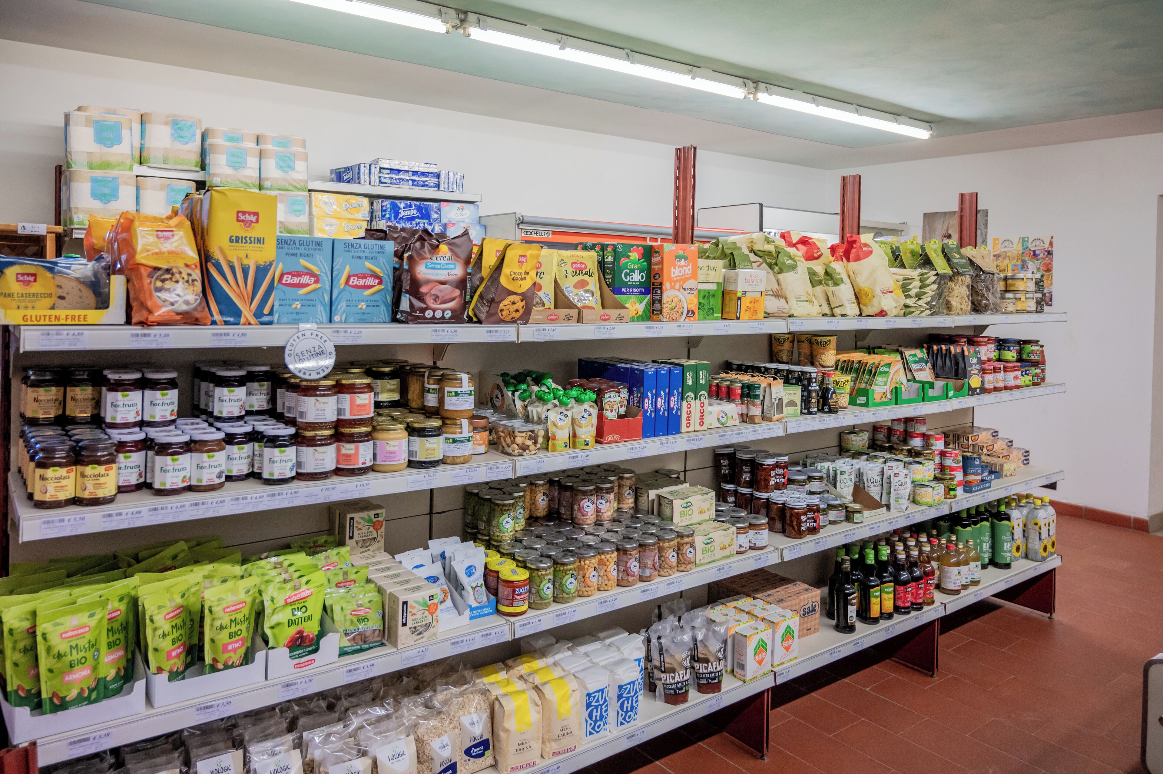 Pasillo de un supermercado con estantes llenos de diversos productos alimenticios, como pasta, conservas y bocadillos.