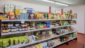 Ein Gang in einem Supermarkt mit Regalen voller verschiedener Lebensmittel, darunter Pasta, Konserven und Snacks.