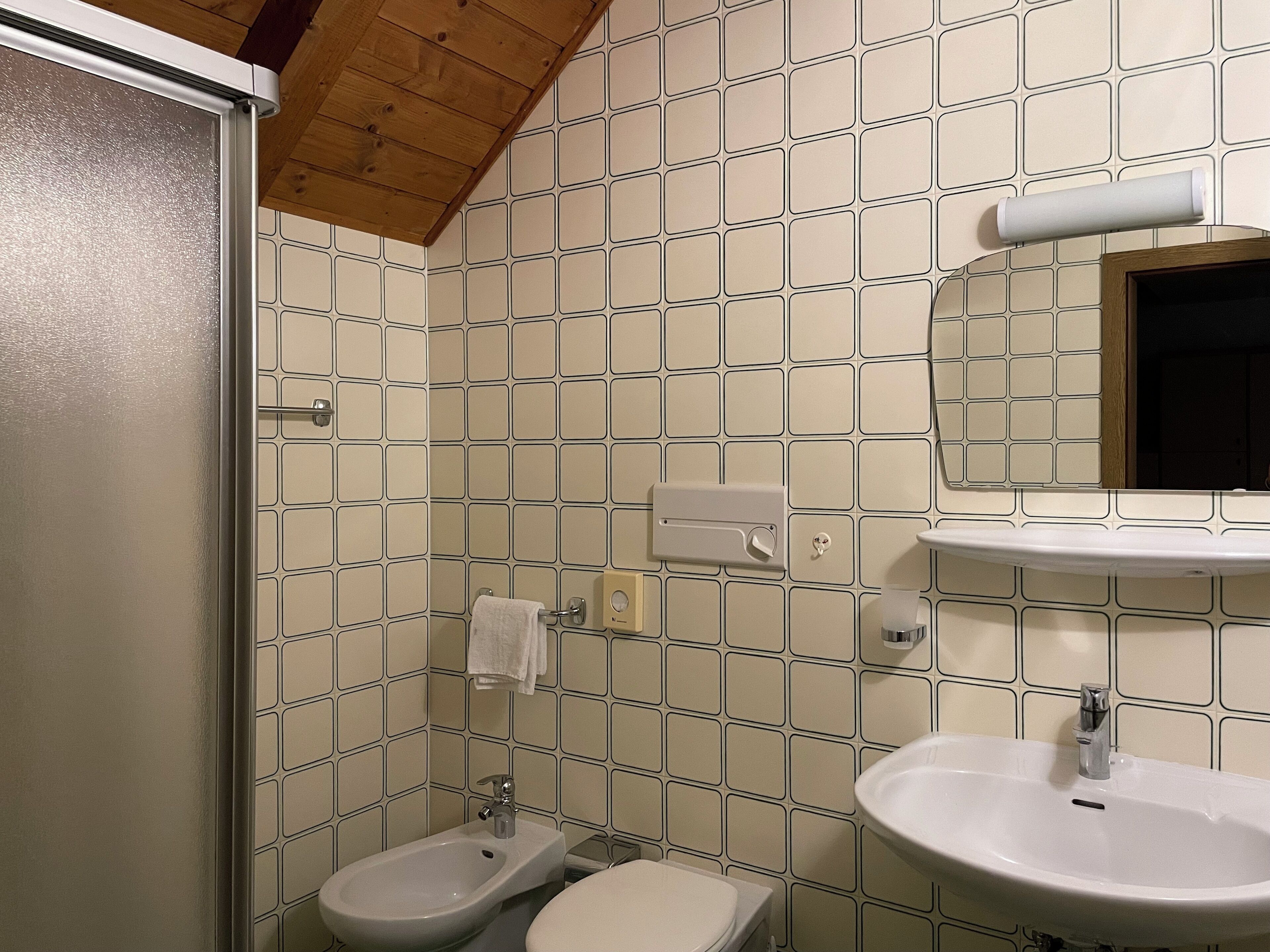 A bathroom with a bidet, toilet, sink, and a mirror.