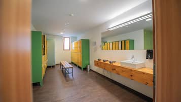 Eine Toilette mit Holzbänken, einem Waschbecken und Schließfächern.
