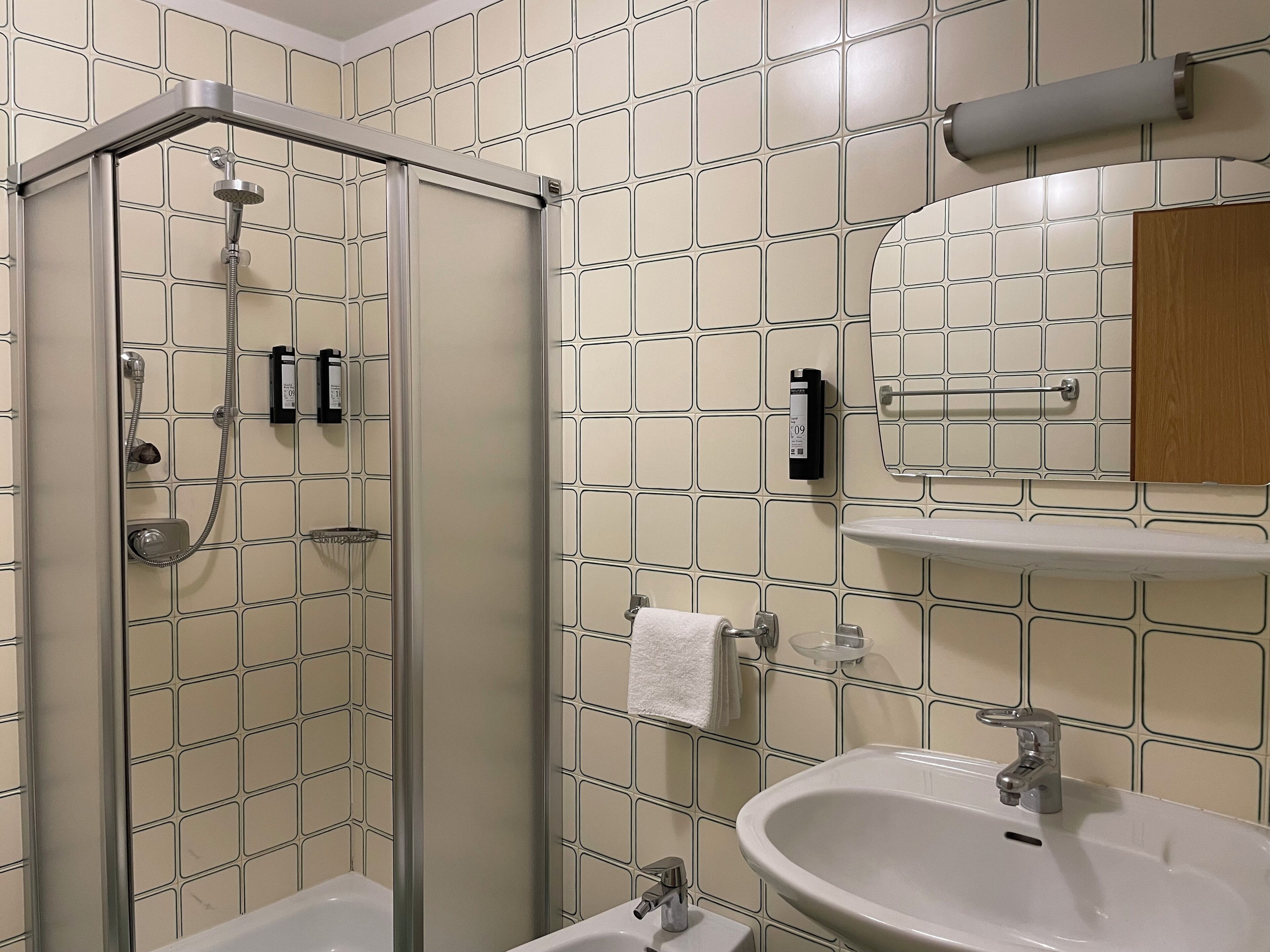 Une salle de bain avec une douche à parois de verre, un lavabo et un miroir.