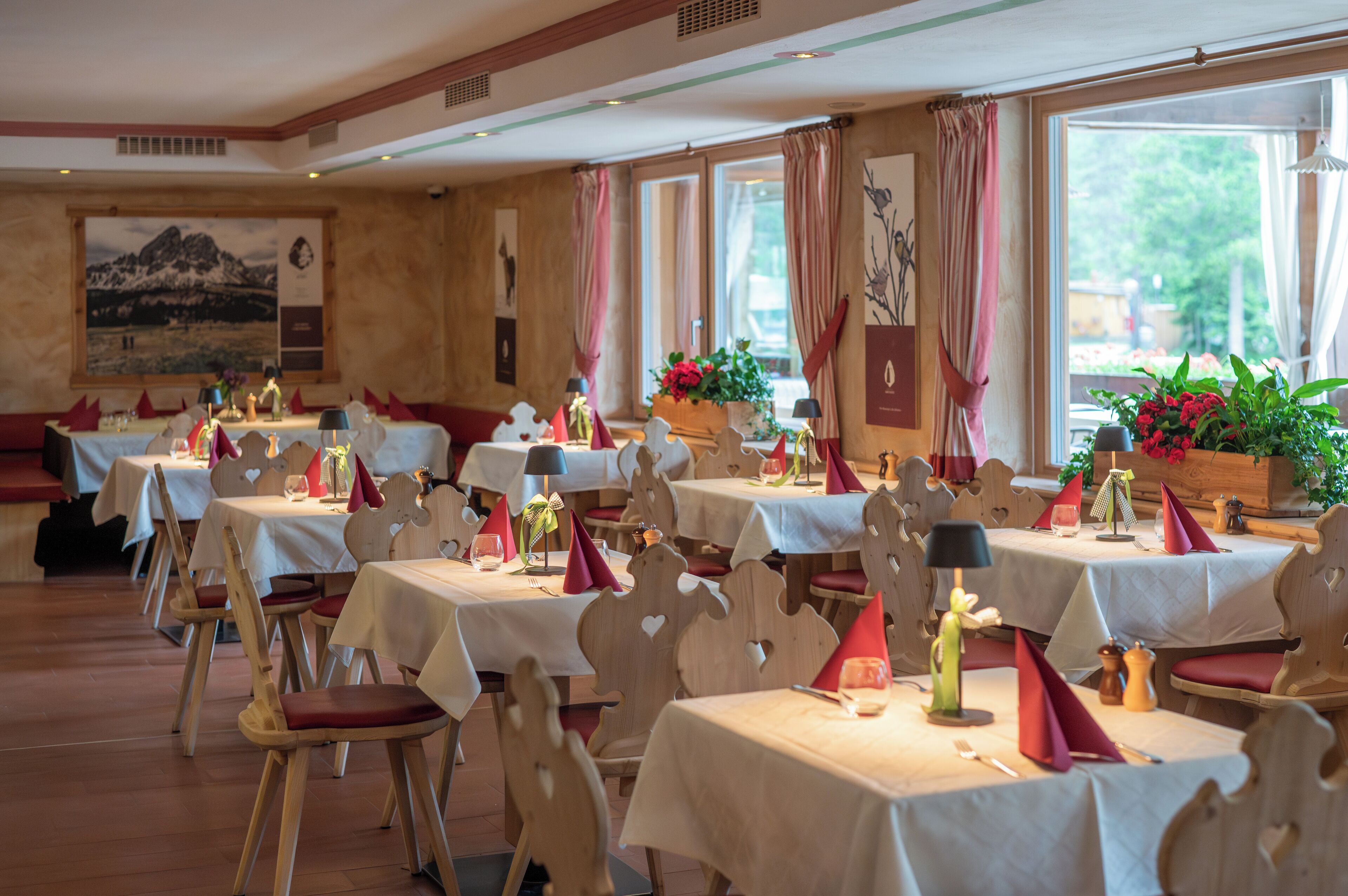 Un restaurante con varias mesas, cada una adornada con manteles blancos, servilletas rojas y velas.