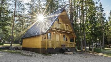 A cabin with a balcony, surrounded by trees.