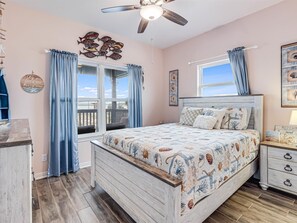 Enjoy a spacious room with a large bed, nightstand, and dresser, plus a balcony with a view of the surrounding area.