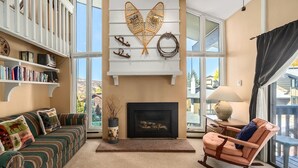 A cozy living room with a fireplace, a rocking chair, a sofa, and a bookshelf. - Hillsider 7 2 Bedroom Townhouse (Steamboat Springs)