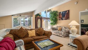 A spacious living room with a large window, a sofa, a coffee table, and a lamp. - Hillsider 7 2 Bedroom Townhouse (Steamboat Springs)