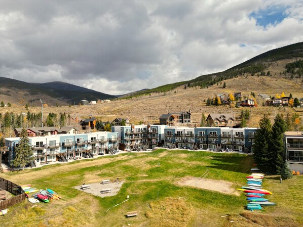 A residential area with multi-story buildings, a grassy field, and kayaks lined up. - Yacht Club 27 1 Bedroom Condo (Dillon)
