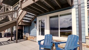 A building with a covered outdoor area, two blue Adirondack chairs, and a staircase leading to an upper level. - Yacht Club 27 1 Bedroom Condo (Dillon)