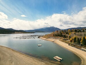 A lakeside view with a marina, sandy beach, and mountains in the background. - Yacht Club 27 1 Bedroom Condo (Dillon)