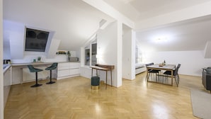 A spacious loft apartment with a kitchen, dining area, and a large window.