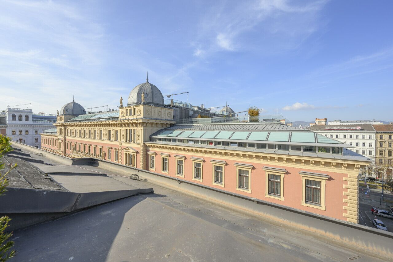 A historic building with a prominent dome and classical architecture, featuring a large glass extension.