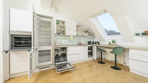 A modern kitchen with white cabinetry, a built-in oven, a dishwasher, and a skylight.