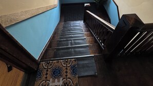 Una escalera con una pared azul, barandilla de madera y un tapete estampado al pie.