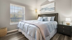 A bedroom with a bed, bedside table, lamp, and a wall-mounted light fixture.