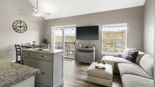 A modern kitchen with a granite countertop, a ceiling fan, and a dining area with chairs.
