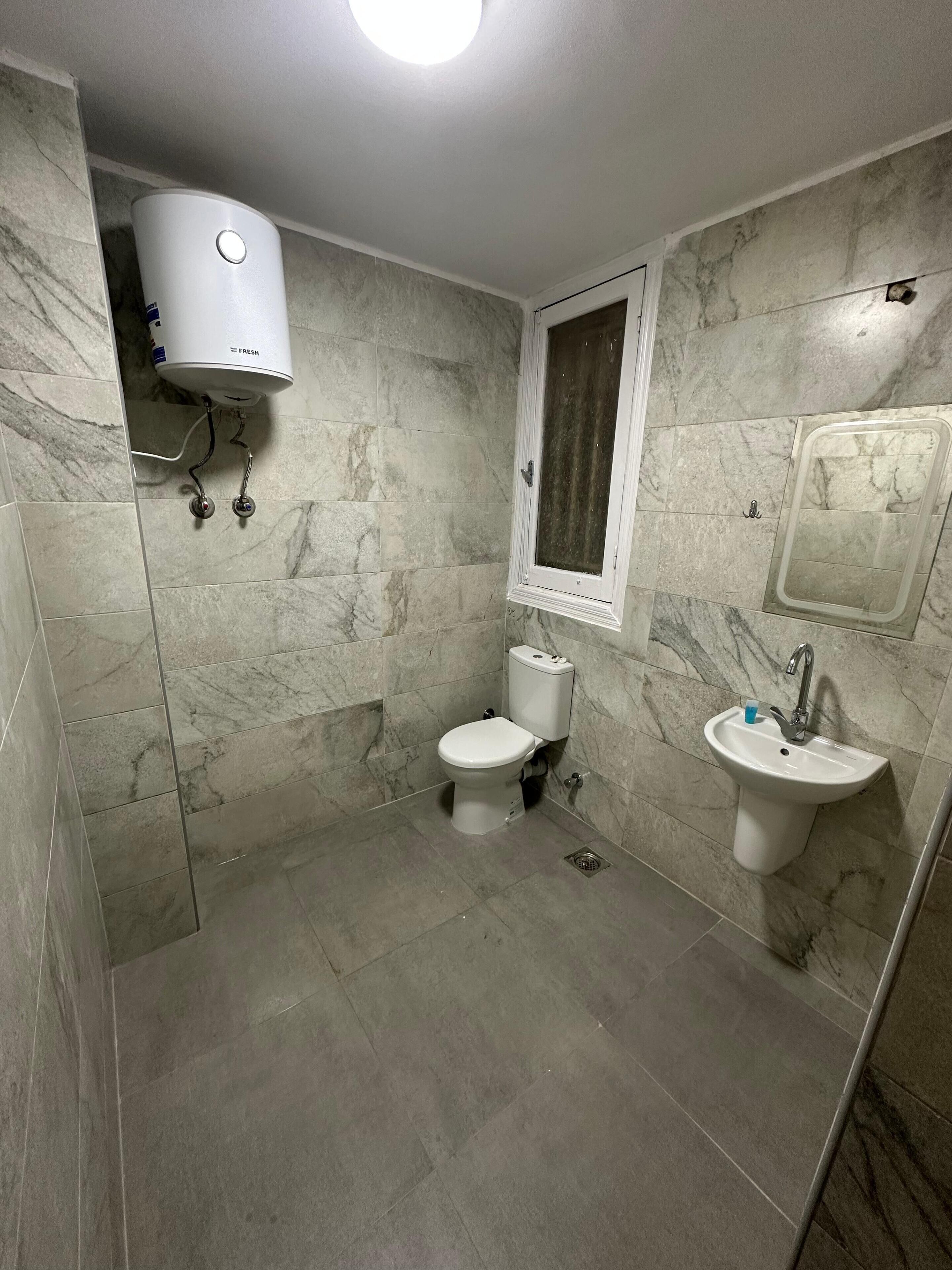 Un baño con inodoro, lavabo y zona de ducha.