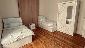 Une chambre avec un plancher en bois, un lit, une armoire et un grand miroir.