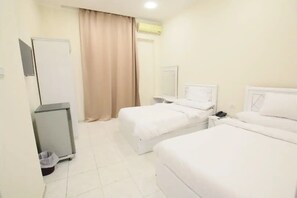 Two single beds with white linens, a wall-mounted TV, and a bedside table with a lamp.