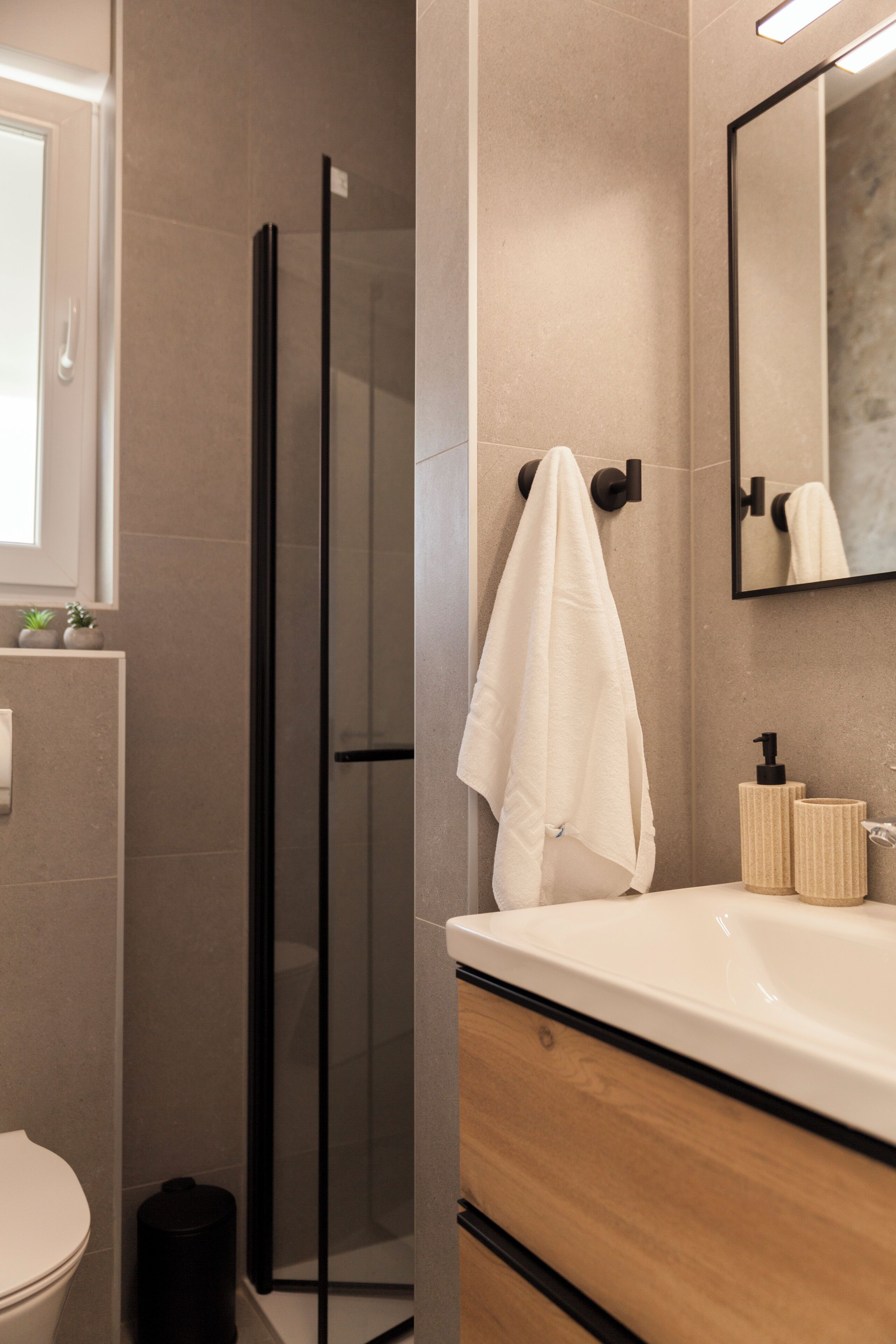 A modern bathroom with a glass shower enclosure, a white sink, and a mirror above it.