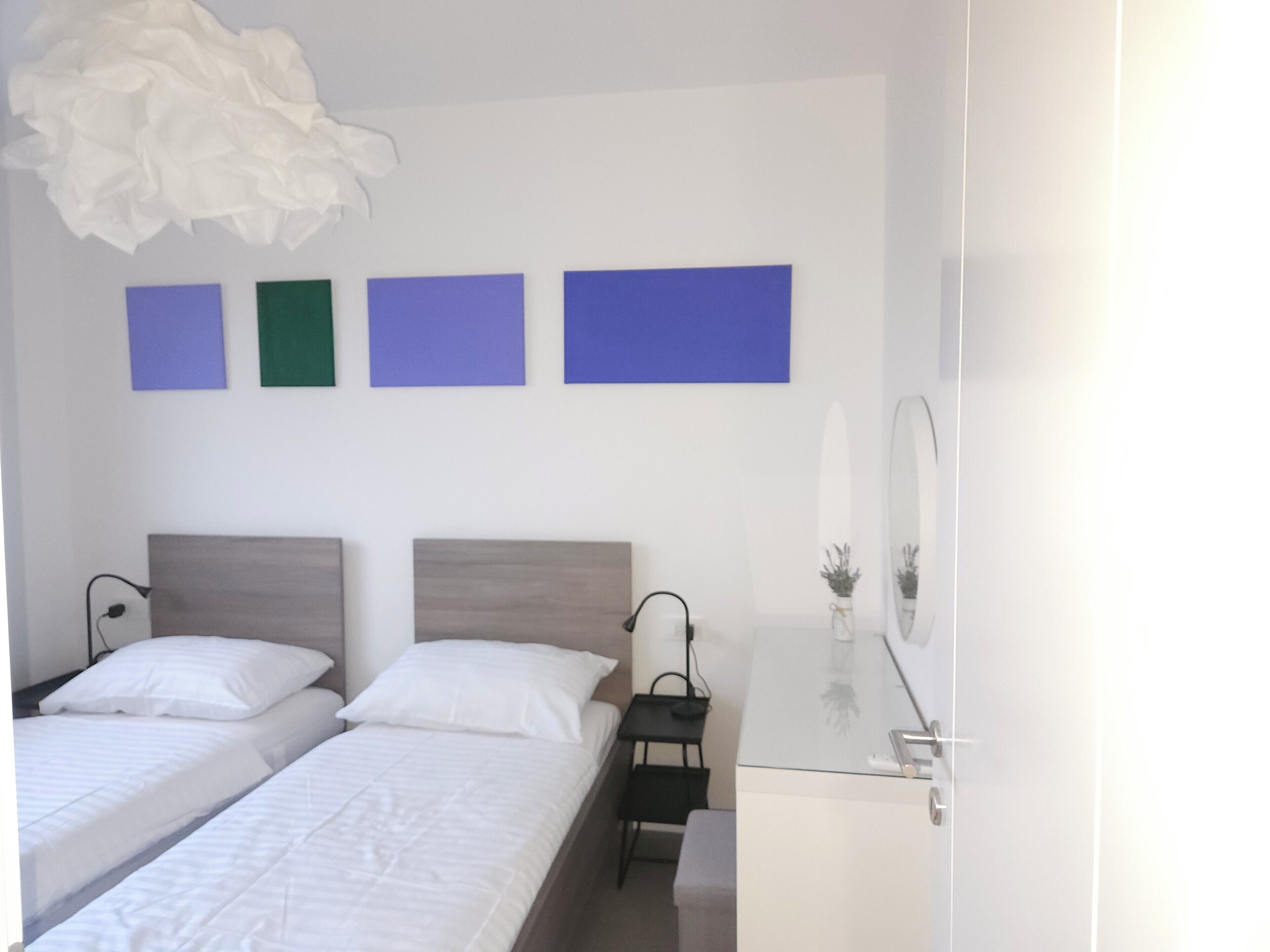 A hotel room with two beds, a desk, and a mirror.