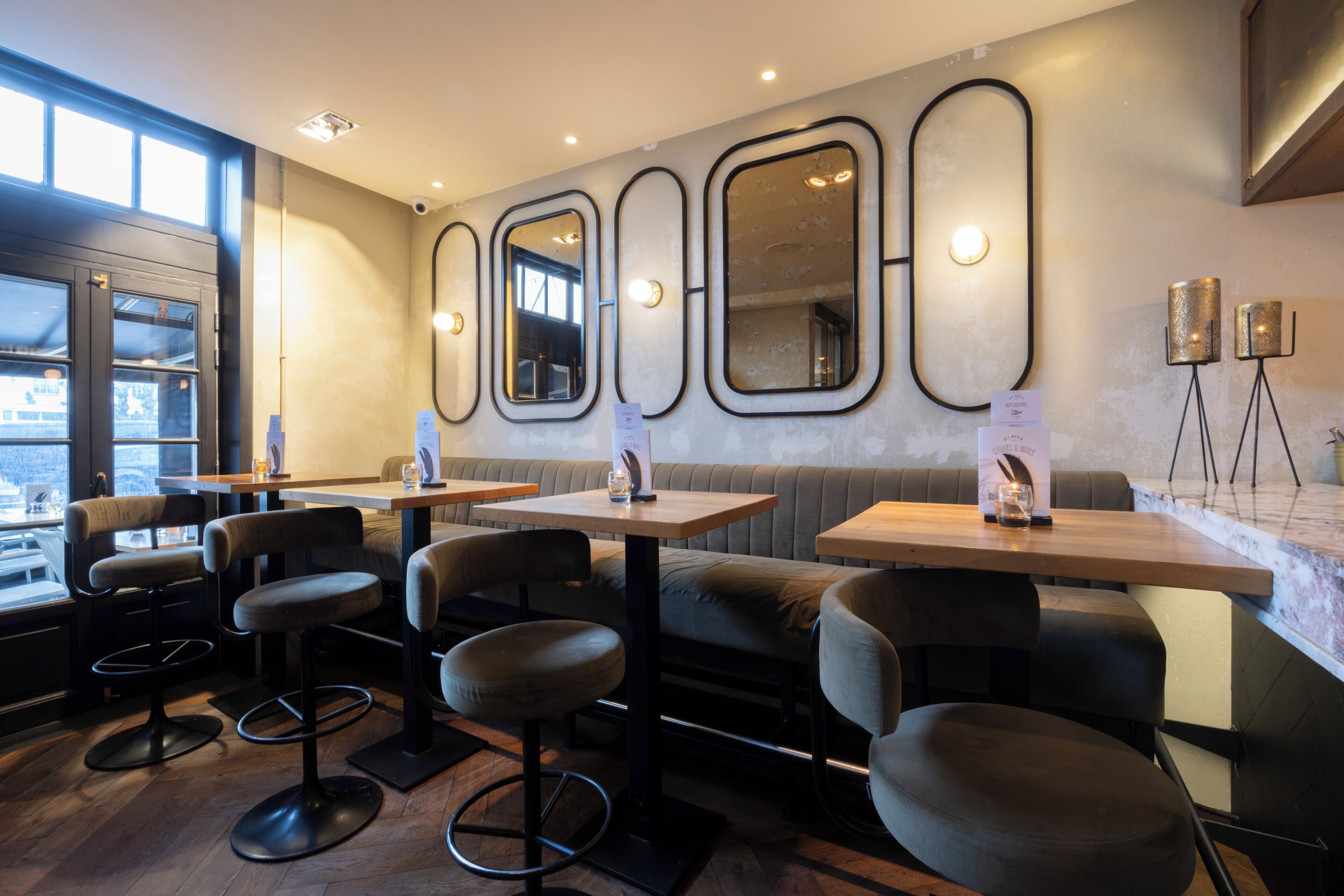 Een restaurantinterieur met hoge tafels, barstoelen en een zithoek.