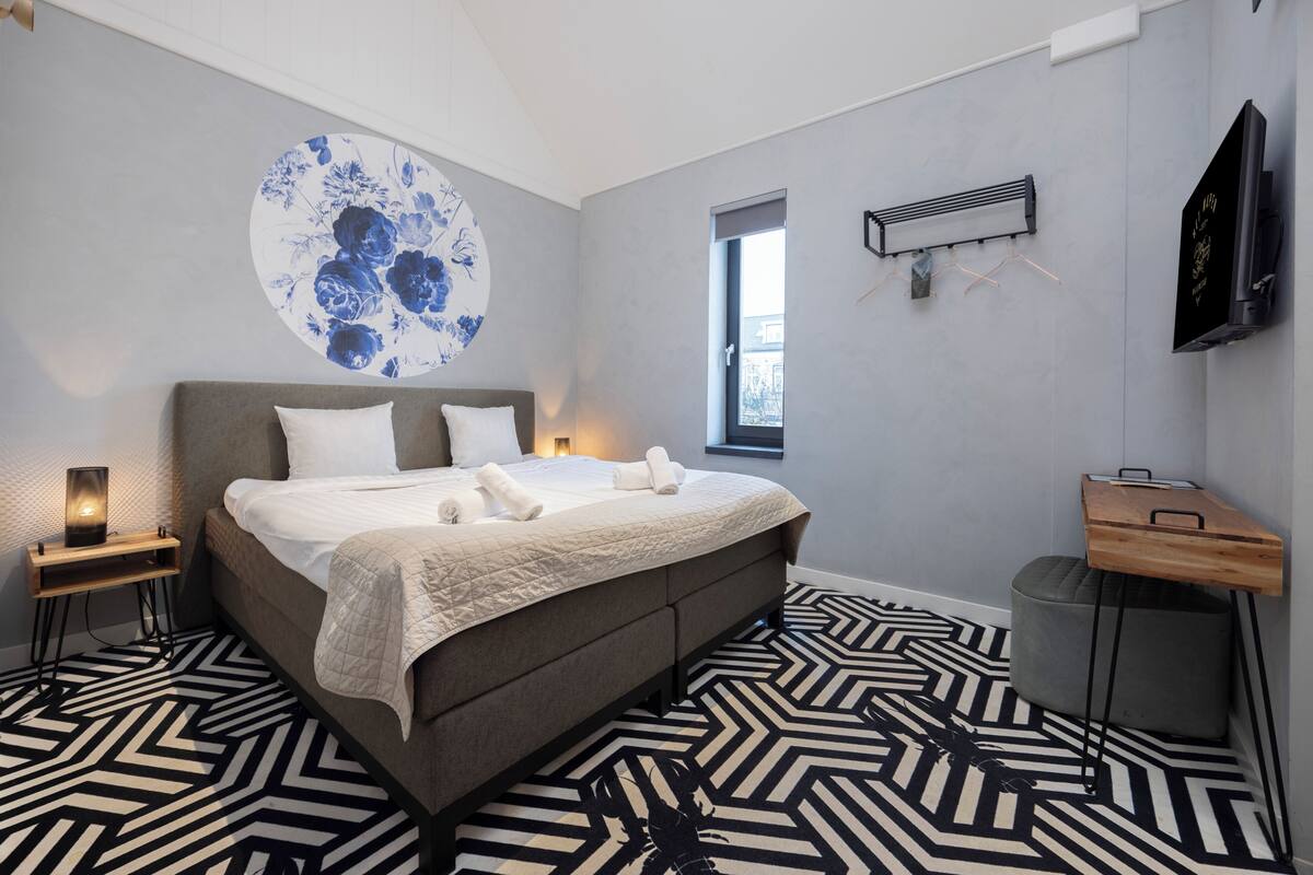 A modern bedroom with a large bed, a wall-mounted TV, and a window.