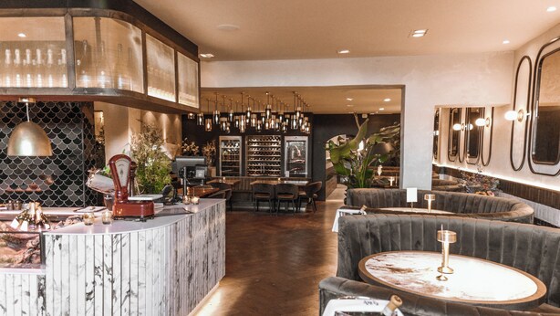 A modern bar area with a marble counter, plush seating, and a wine rack in the background. - Het Wapen in Willemstad (Willemstad)
