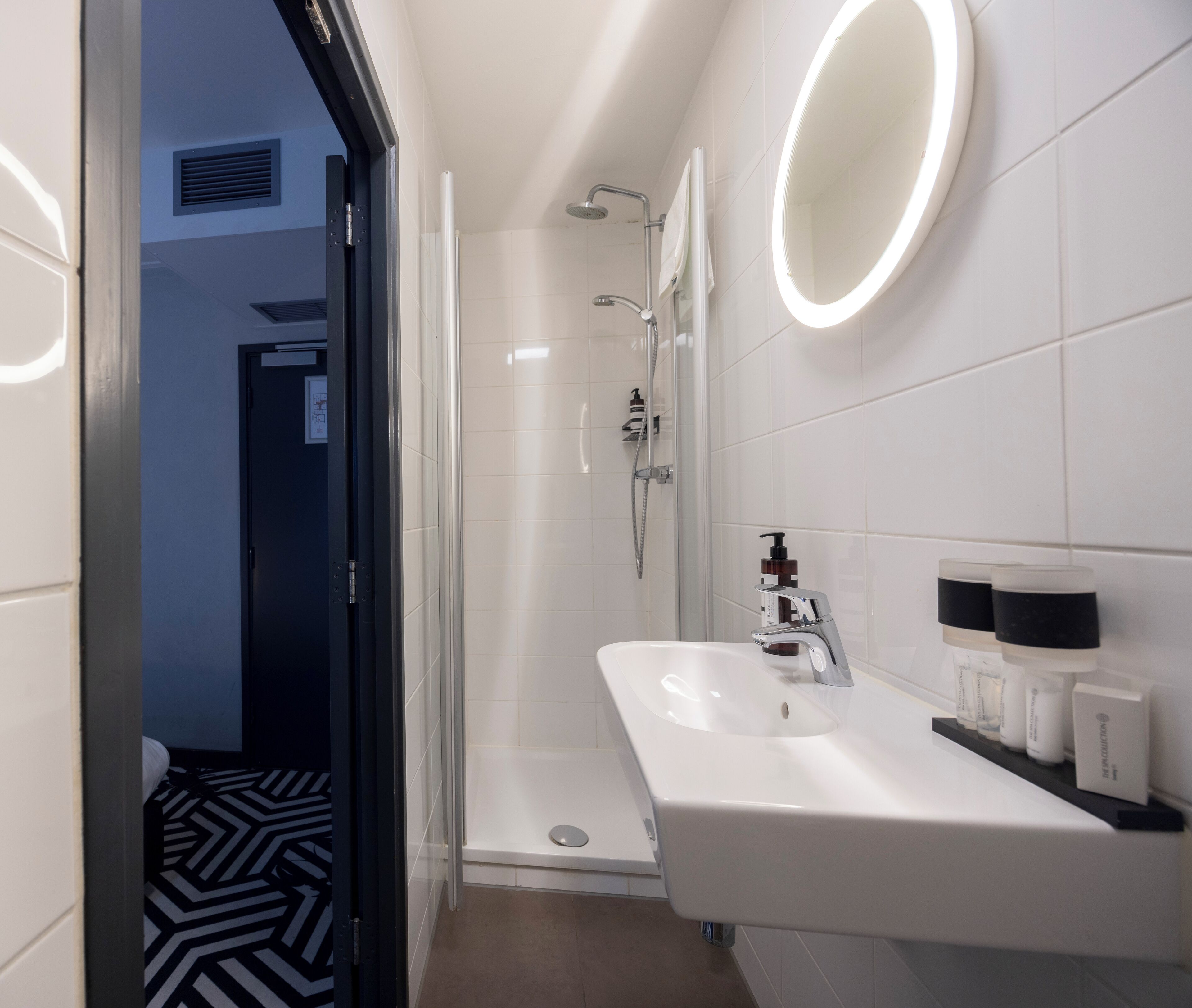 A modern bathroom with a shower, a sink with a mirror, and toiletries on the counter.