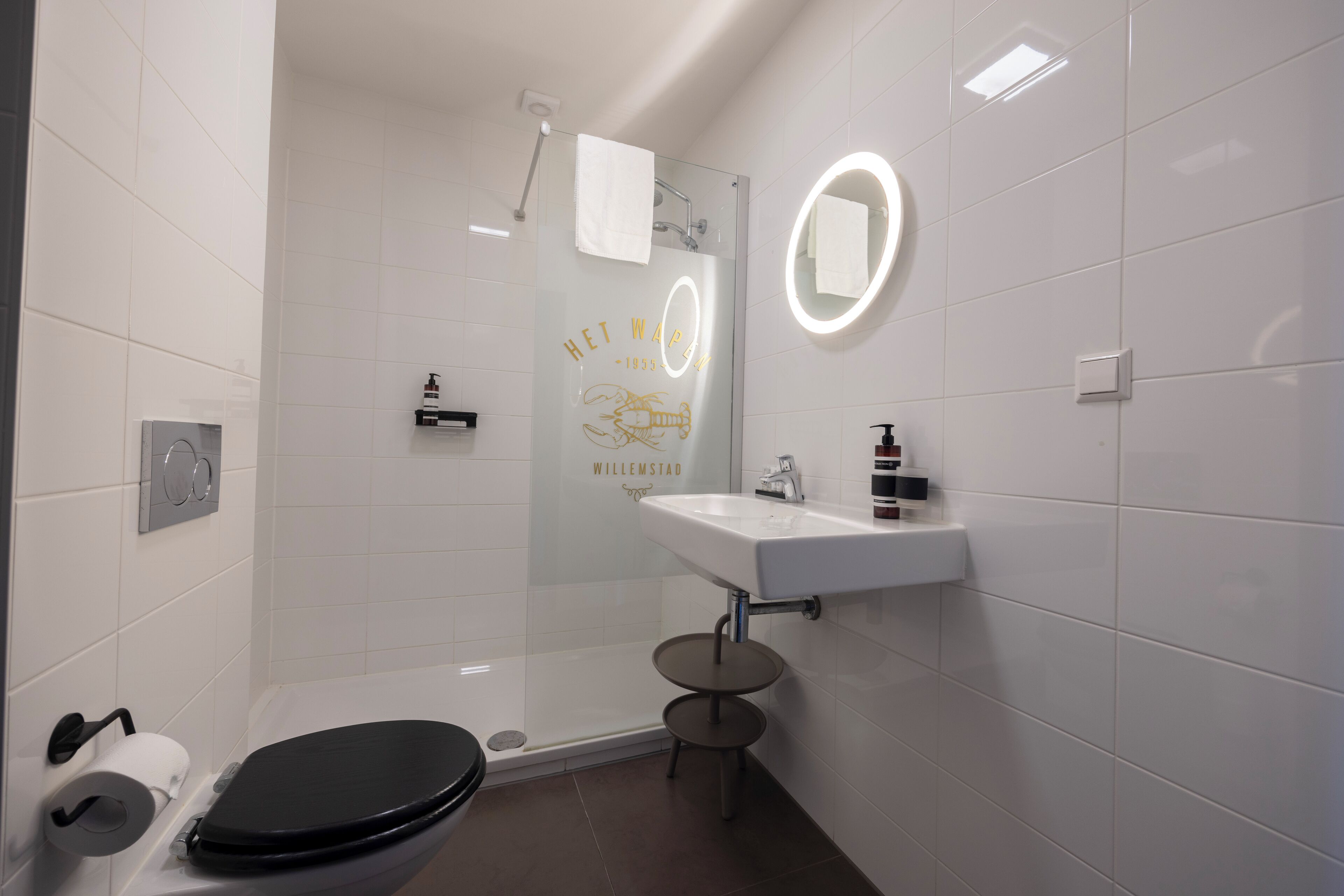 Une salle de bain moderne équipée de toilettes, d’un lavabo et d’une douche à parois de verre.