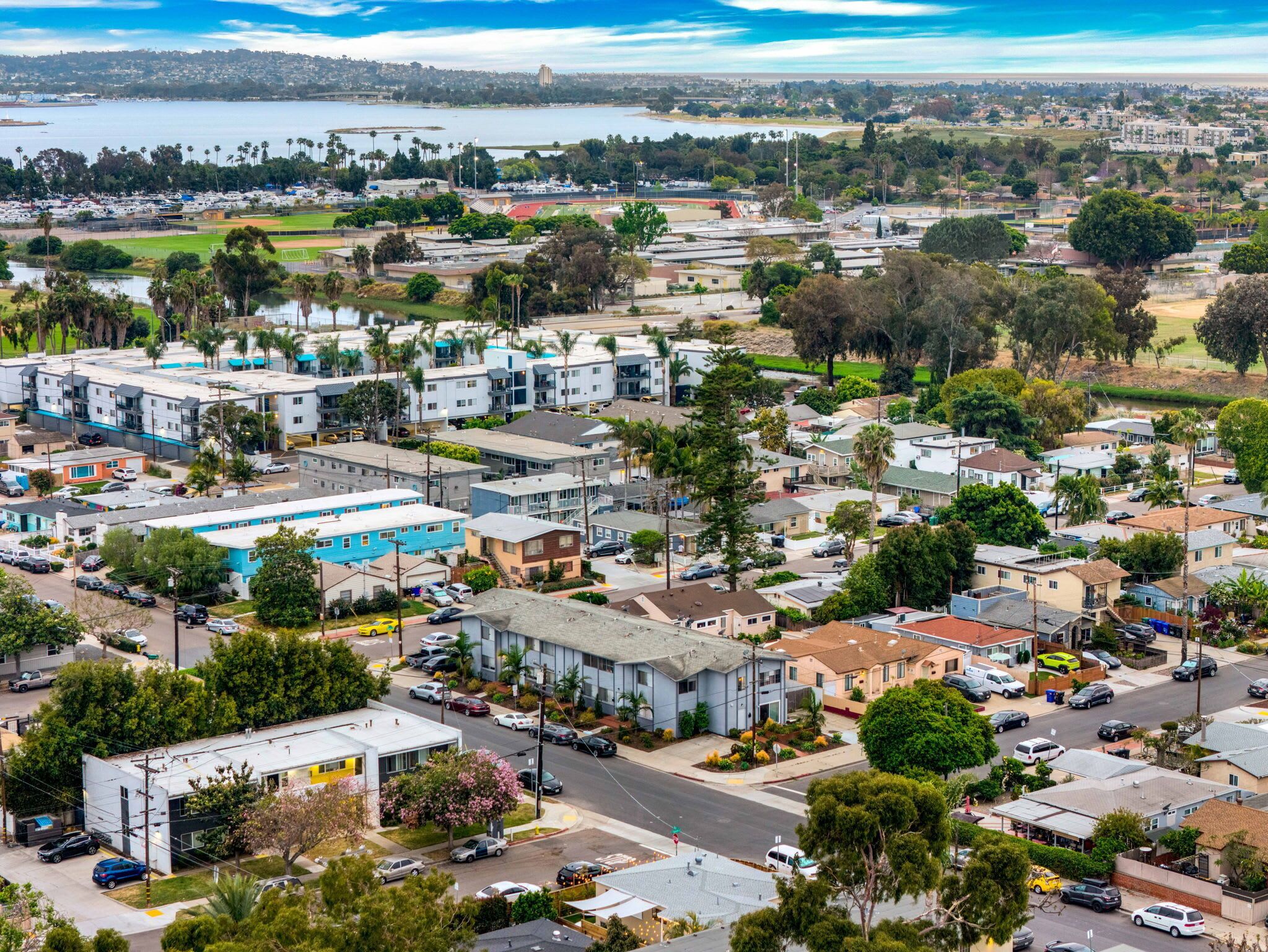 A residential area with modern houses, a road, and a body of water in the background.
