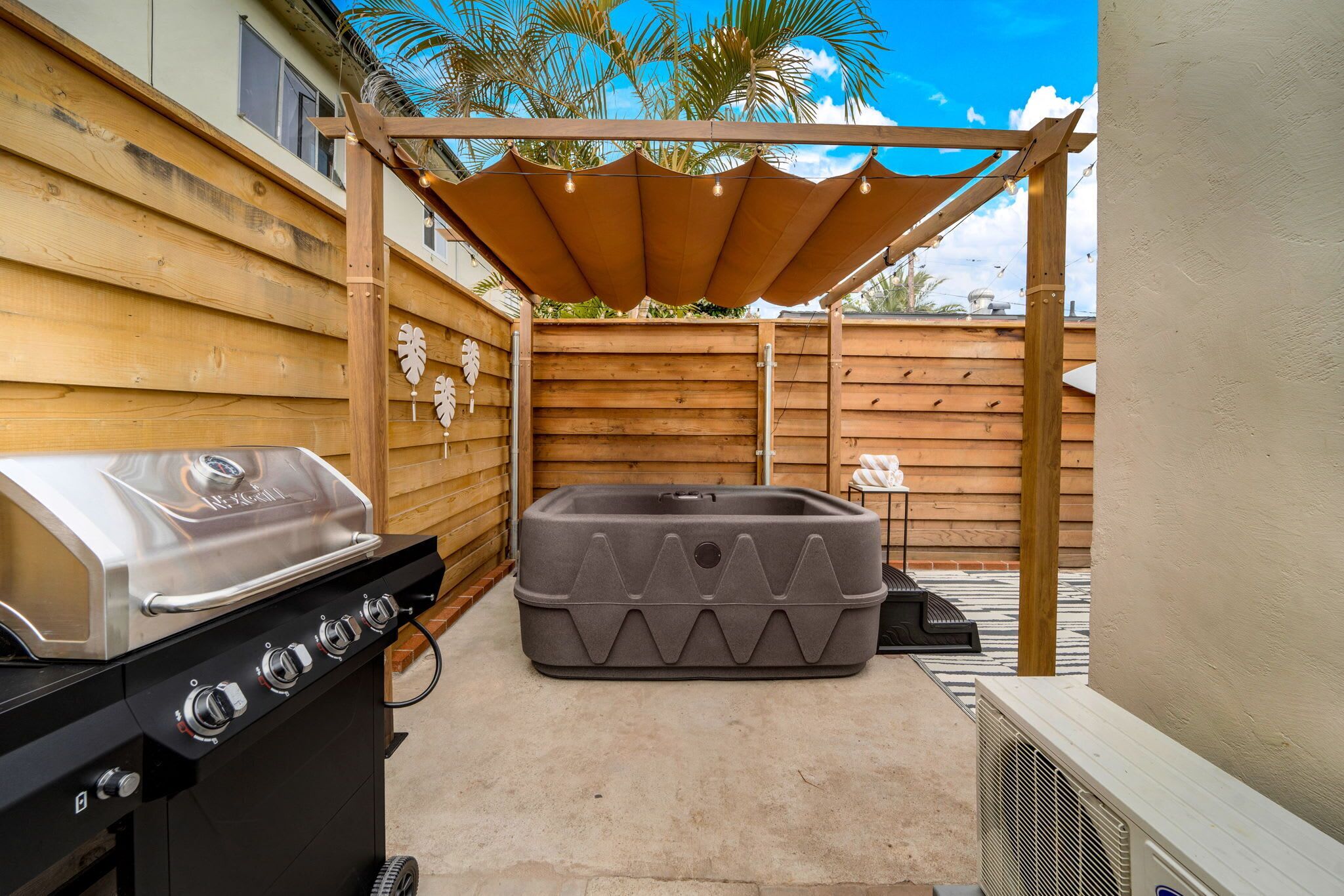 Un jardin avec un barbecue, un jacuzzi et un patio couvert.