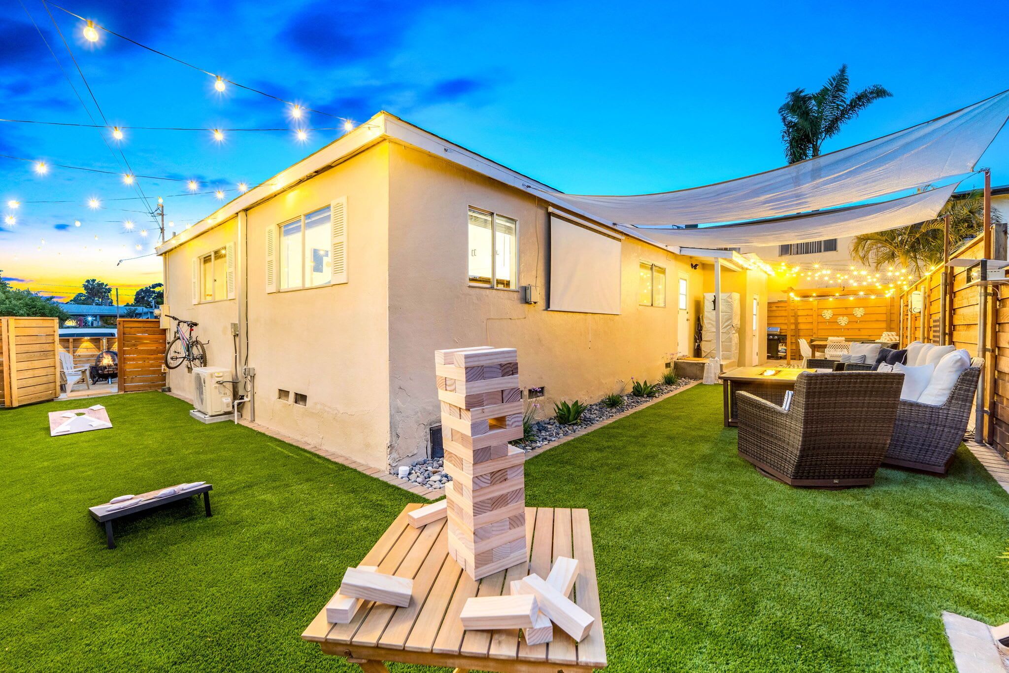 A modern house with a patio area, a wooden play structure, and outdoor furniture.