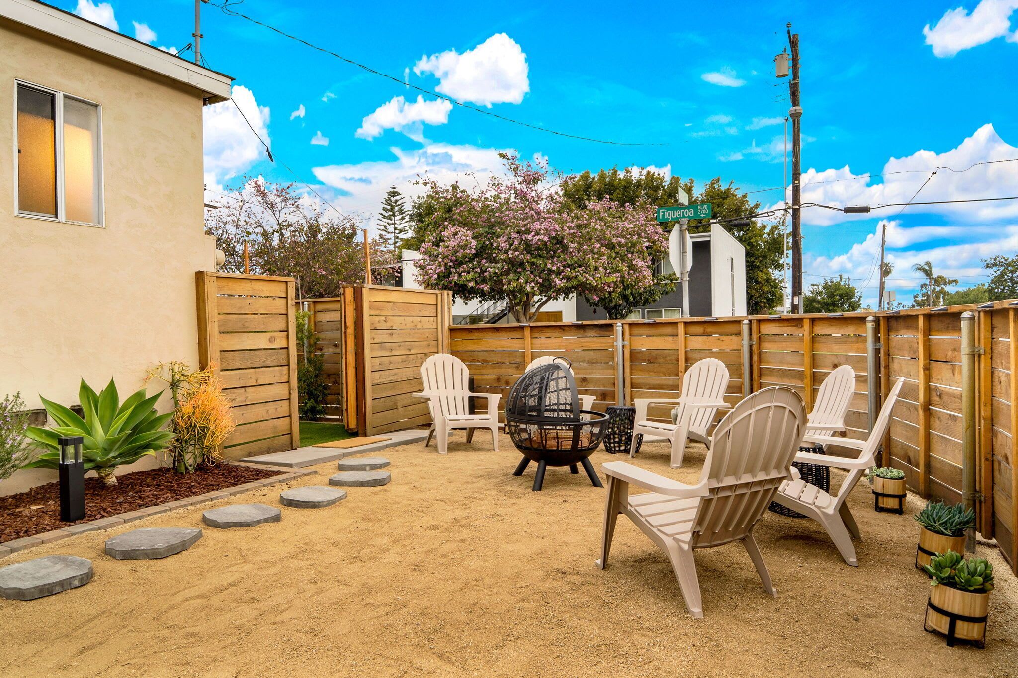 A backyard with a wooden fence, outdoor seating, and a pergola.