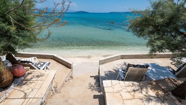 A beachside patio with lounge chairs and a view of the sea. - Beachfront villa Mihovil w. beach access (Kastela)