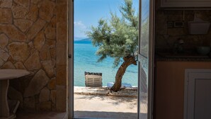 A stone wall, a door leading to a beach with a tree, and a small table. - Beachfront villa Mihovil w. beach access (Kastela)